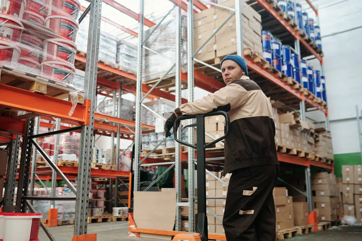 A warehouse operator moving palletised goods through racking