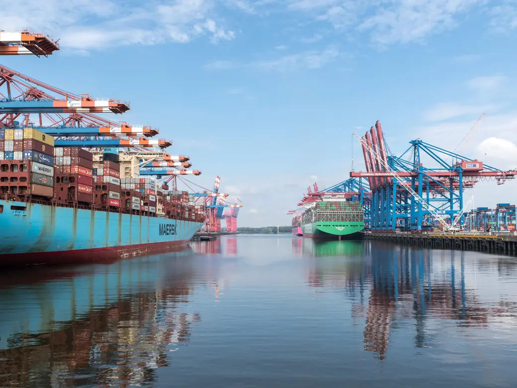 A container ship berthed at a port terminal beside loading cranes
