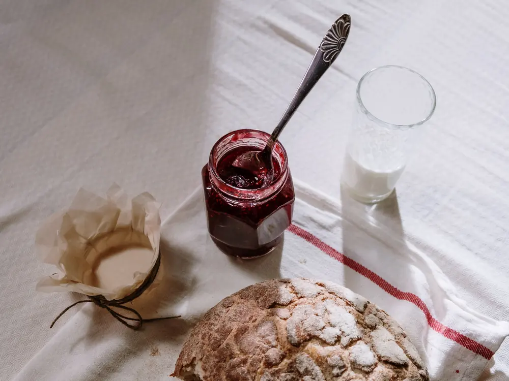 An open jar of dark red fruit preserve