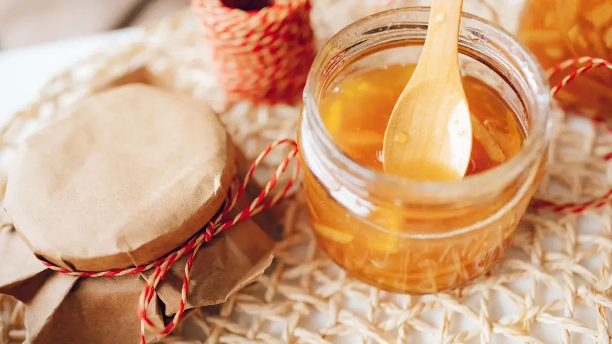 An open jar of syrup with a wooden serving spoon