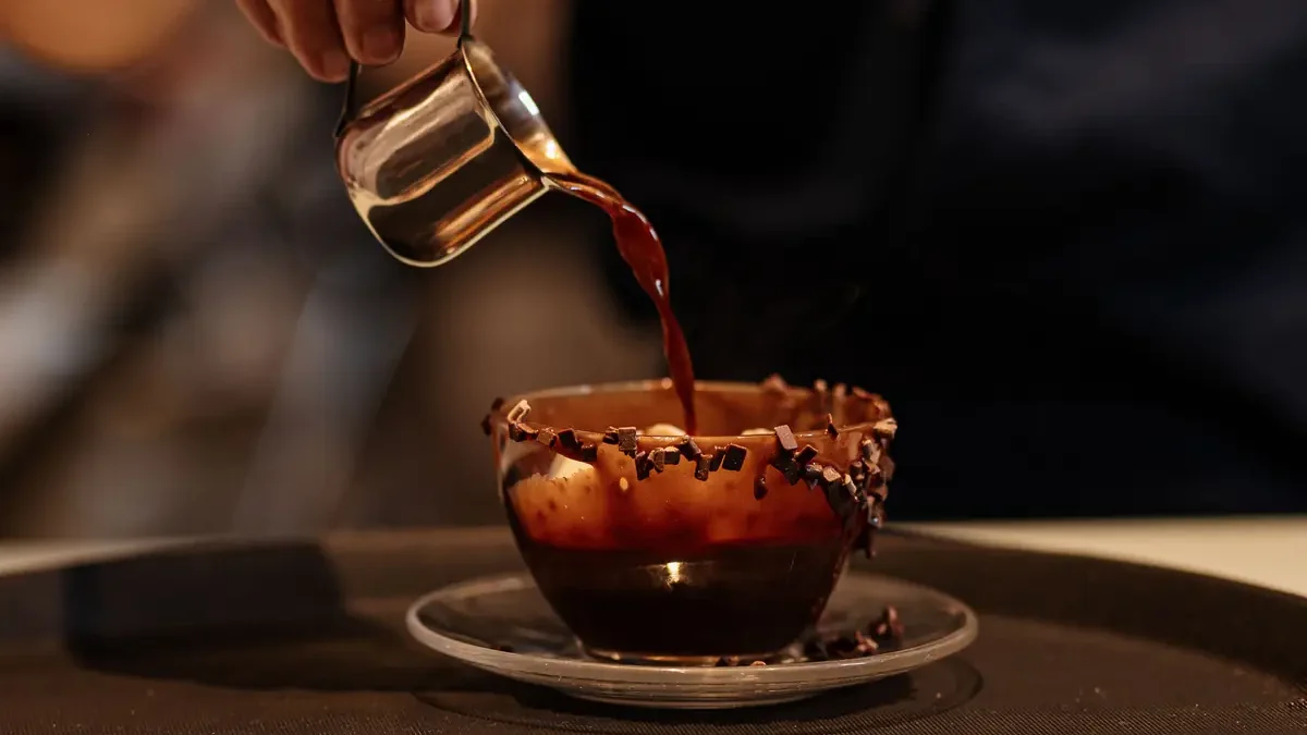 Dark date syrup being poured into a glass alongside whole dates