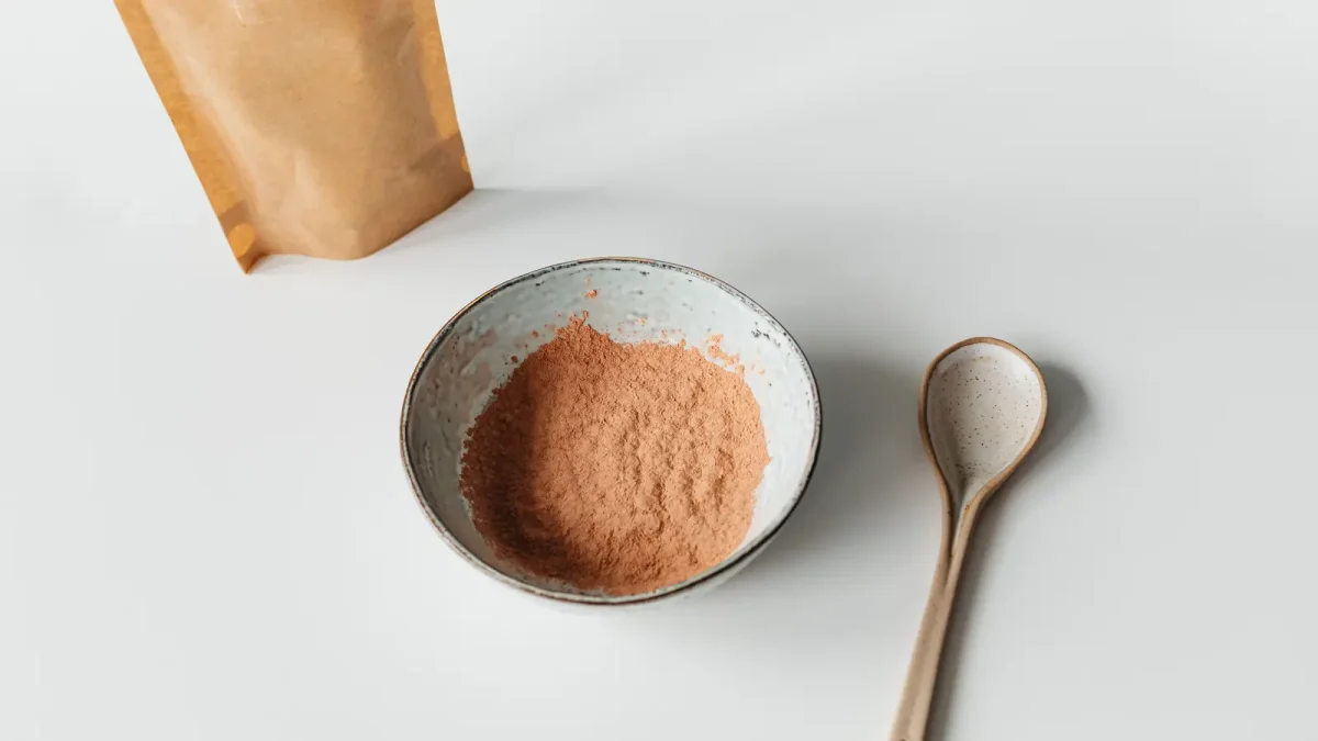 Carob powder in a small bowl with a wooden spoon