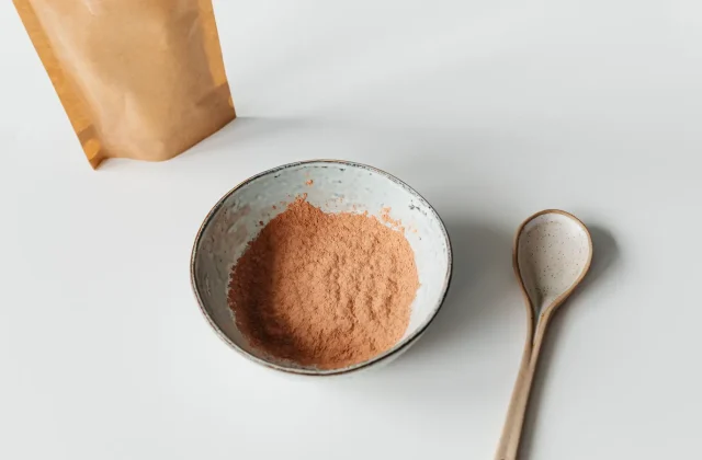 Carob powder in a small bowl with a wooden spoon
