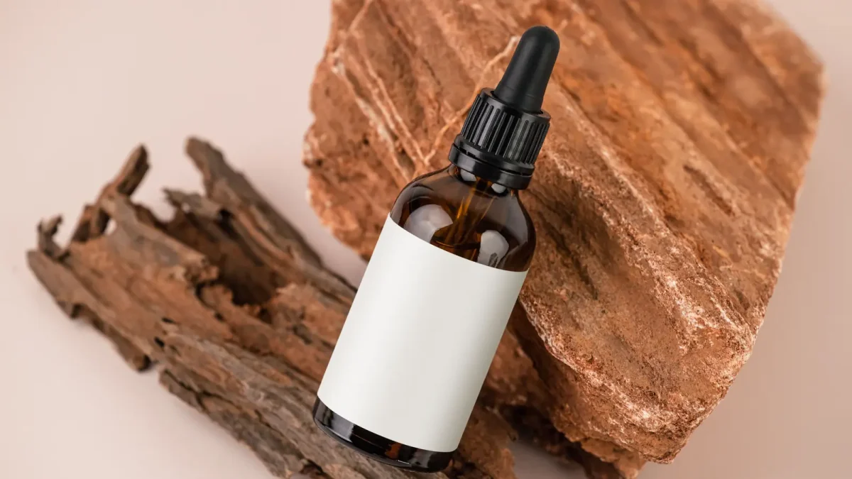 An amber dropper bottle of seed oil against wood