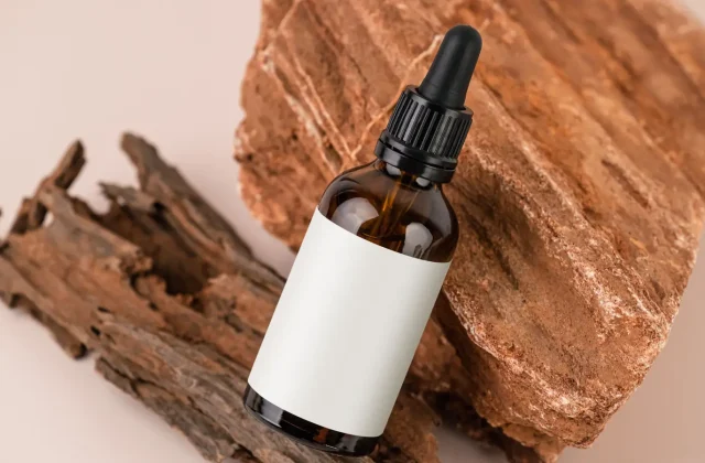 An amber dropper bottle of seed oil against wood