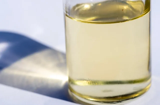 A glass of pale refined olive oil in sunlight