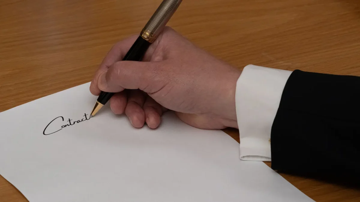 A hand signing a document with a fountain pen